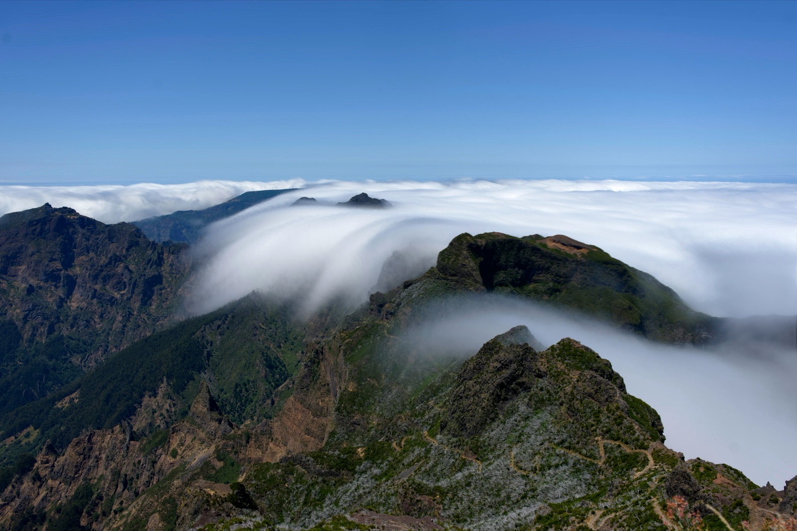 Clouds flowing over a Madeira mountain peak at golden hour.